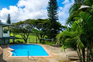 a swimming pool in front of a house with trees at Kapalua Golf Villa 18T 1&2 in Kahana
