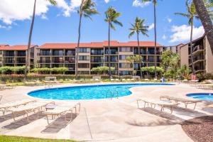 a resort swimming pool with chairs and palm trees at Papakea F105 in Lahaina