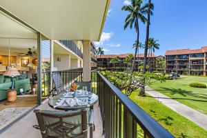 a balcony with a table and chairs and palm trees at Papakea B204 in Lahaina