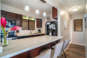 a kitchen with a large counter with white chairs at Hono Kai A5 in Wailuku