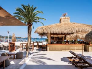 a beach bar with chairs and a palm tree at Zel Mallorca in Palmanova