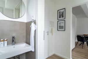 a white bathroom with a sink and a mirror at Green Flat Düsseldorf First in Düsseldorf