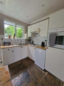 cocina con electrodomésticos blancos y ventana grande en Molly Dishwasher Shepherds Hut, en Frant