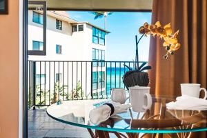 a glass table with chairs and a balcony with a view at Noelani 212 in Kahana