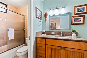 a bathroom with a sink and a toilet and a mirror at Noelani 212 in Kahana