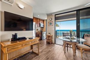 une cuisine et une salle à manger avec une grande télévision et une table à manger dans l'établissement Noelani 214, à Kahana