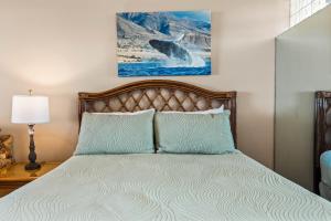 une chambre avec un lit et un tableau au mur dans l'établissement Noelani 214, à Kahana 17 autres photos