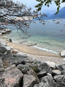 a beach with some rocks and boats in the water at Absentia 1763 Garda Boutique Home in Brenzone sul Garda