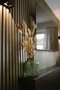 a green vase with flowers on a table in front of a mirror at Green Flat Düsseldorf First in Düsseldorf