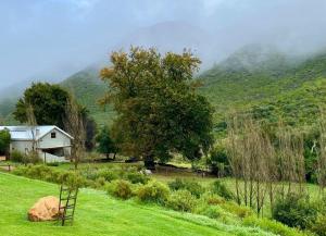 a house in a field with mountains in the background at Pat Busch Mountain Reserve in Robertson