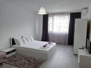 a white bedroom with a white bed and a window at Apartment Danilia in Sandanski