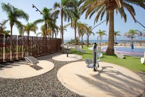 un parque con parque infantil con piscina y palmeras en Casa Siryo, en Castillo del Romeral