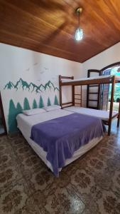 a bedroom with a bed with a mountain mural on the wall at Hostel Na Praia - Hospedagens e eventos in Ubatuba +69 photos