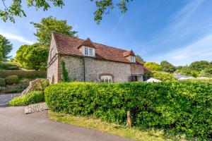 an old stone house with a large hedge at Beachy Barn in Eastdean