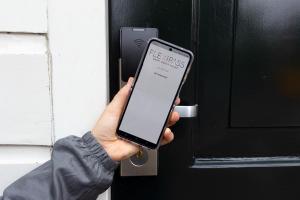 una persona sosteniendo un teléfono inteligente delante de una puerta en SWEETS - Kattenslootbrug en Ámsterdam