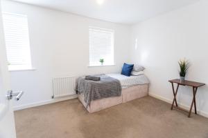 a bedroom with a bed and a table and windows at April Disc - Long Stay - Contractors in Bristol