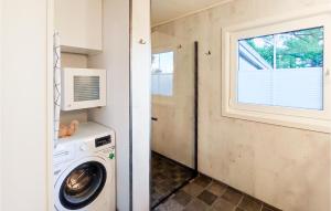 a laundry room with a washing machine and a window at The Woodpecker Cottage Tree in Salterød