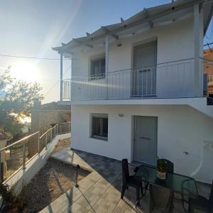 a white house with a table and a balcony at Ionian Avra Apartment in Athanion