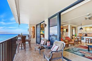 a living room with chairs and a balcony with the ocean at Hololani A402 in Kahana