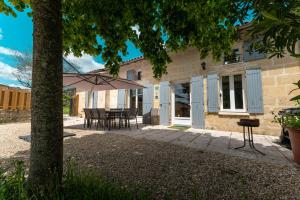 Saint-Magne-de-CastillonにあるL Escale des Vignes GITE proche Saint Emilion Chateau Beynatのパティオ(テーブル、傘付)