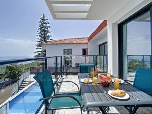 a table with food and drinks on a balcony at Casa Teixeira by Atlantic Holiday in Estreito da Calheta