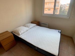 ein kleines Schlafzimmer mit einem Bett und einem Fenster in der Unterkunft Appartement Hesperides avec Terrasse in Cannes