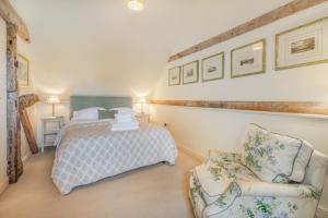 a bedroom with a bed and a chair at Beachy Barn in Eastdean