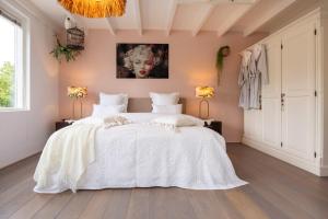 um quarto com uma grande cama branca com lençóis brancos em Vakantiehuis De Zeeparel em Zandvoort