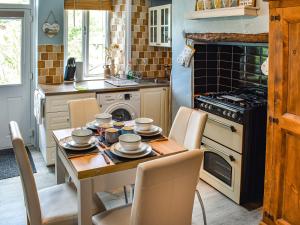 y cocina con mesa, sillas y fogones. en Beeswax Cottage, en Dalton-in-Furness