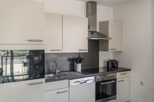 a kitchen with white cabinets and a sink at Ferienhaus Kesselgrub in Altenmarkt-Zauchensee in Altenmarkt im Pongau