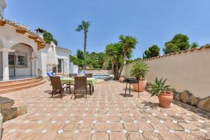 a patio with a table and chairs and a pool at Villas Guzman - Sebastian in Moraira