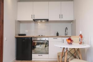 a kitchen with white cabinets and a white table at Angela's flat studio - Dassia Corfu in Kato Korakiana +10 photos