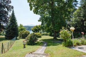 a path through a garden with a lake in the background at Villa Fernblick in Velden am Wörthersee
