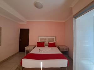 a bedroom with a large bed with red pillows at Jate Guest House in Maseru