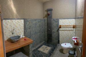 a bathroom with a shower and a sink and a toilet at Kubu Padi Wooden House in Pemuteran