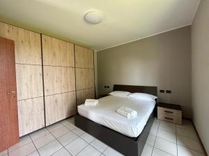 1 dormitorio con 1 cama grande y armarios de madera en Appartamento Mimosa - Immobili e Soluzioni Rent, en Brembate