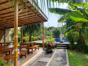 a patio with wooden tables and benches and a pool at Kubu Padi Wooden House in Pemuteran