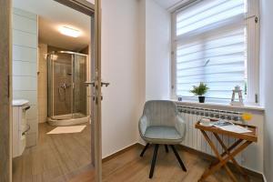 a bathroom with a shower and a chair and a desk at Exclusive Palace App 3 Varaždin in Varaždin