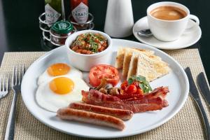 a plate of breakfast food with eggs bacon toast and a cup of coffee at Protea Hotel by Marriott Gaborone Masa Square in Gaborone