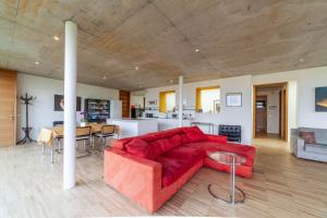 a living room with a red couch and a kitchen at Villa Alvarium in Schenna