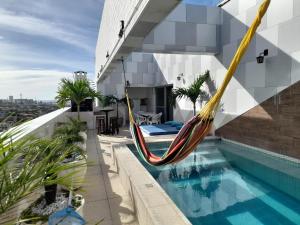 eine Hängematte auf dem Dach eines Hauses mit Pool in der Unterkunft luxuosa cobertura praia do futuro 1002 in Fortaleza