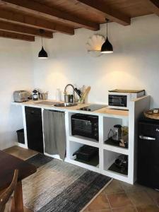 une cuisine avec un évier et un micro-ondes dans l'établissement Uzès proche,charmant pied a terre avec terrasse, à La Bastide-dʼEngras