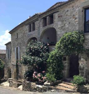 un vieux bâtiment en pierre avec des fleurs devant lui dans l'établissement Uzès proche,charmant pied a terre avec terrasse, à La Bastide-dʼEngras