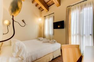 a bedroom with a white bed and a window at Oste del Castello Wellness & Bike Hotel in Verucchio
