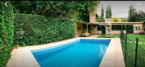 a blue swimming pool in front of a house at Berdina Loft House, Chacras de Coria in Chacras de Coria