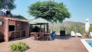 une terrasse en bois avec une table et un parasol dans l'établissement VILLA DU LAC spéciale pour famille avec enfant, à Ríudecañas
