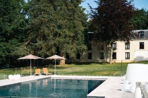 馬夫列的住宿－Hôtel Chateau de Maffliers - Demeures de Campagne，一座带椅子和遮阳伞的游泳池位于一座建筑旁边