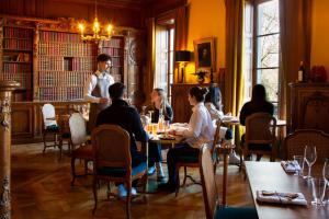 un grupo de personas sentadas en una mesa en un restaurante en Hôtel Chateau de Maffliers - Demeures de Campagne, en Maffliers