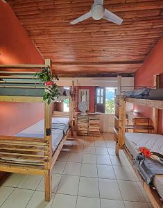 a room with three bunk beds and a ceiling fan at Chapada Backpackers Hostel Agência in Lençóis