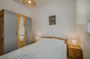 a bedroom with a white bed and a mirror at Apartment Dinka in Čižići